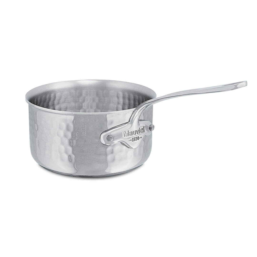 Mauviel M'ELITE hammered stainless steel sauce pan with cast stainless steel handle on a stovetop.