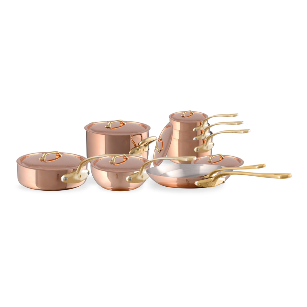 Mauviel M'Heritage M'200 B 14-piece copper cookware set with brass handles, including saucepans and frying pans on a kitchen countertop.