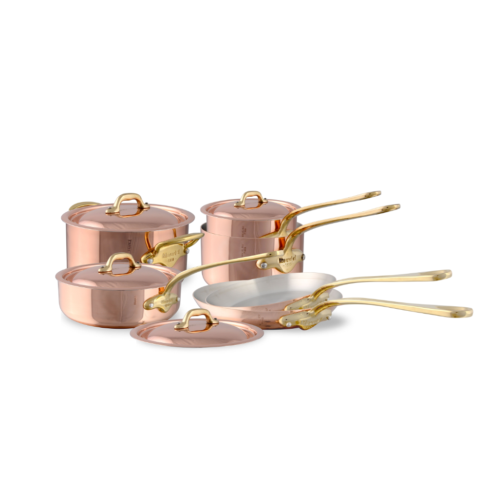 Mauviel M'Heritage M'150 B 10-piece copper cookware set with brass handles, including saucepans and frying pans on a kitchen countertop.