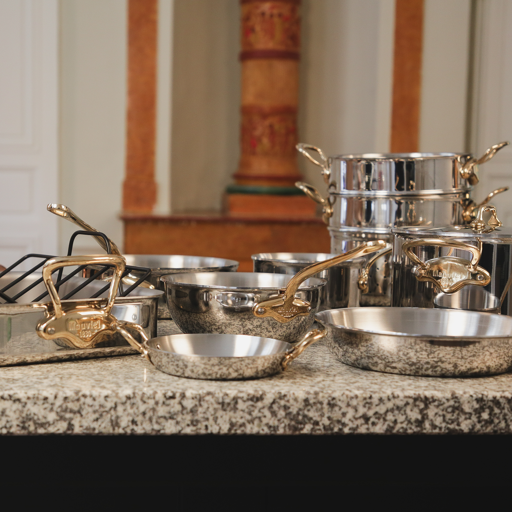 Mauviel M'COOK 5-piece cookware set with brass handles, featuring stainless steel construction and polished finish.