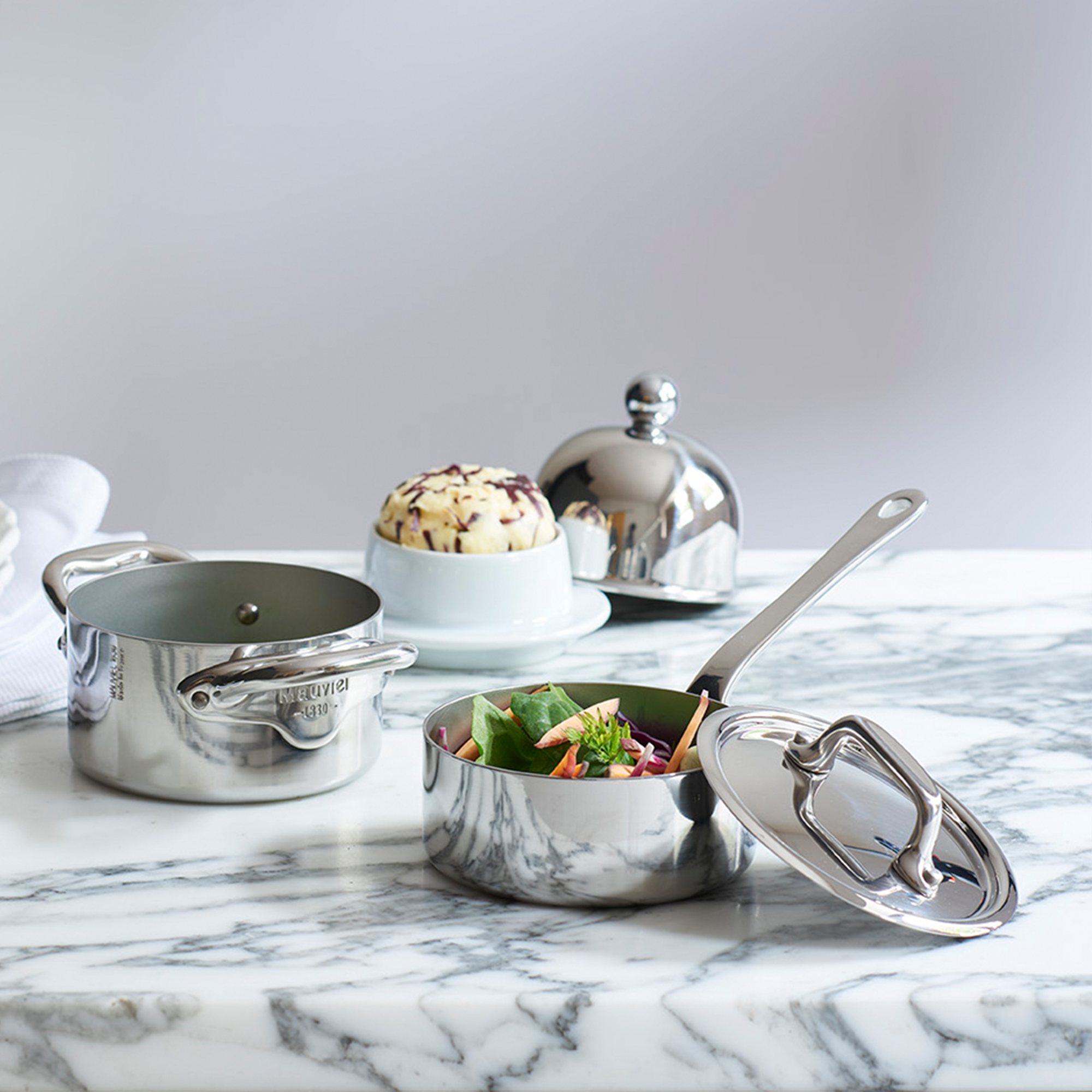 Mauviel M'MINIS stainless steel oval stewpan with brass handles and lid, 0.36-quart capacity, perfect for small cooking tasks.