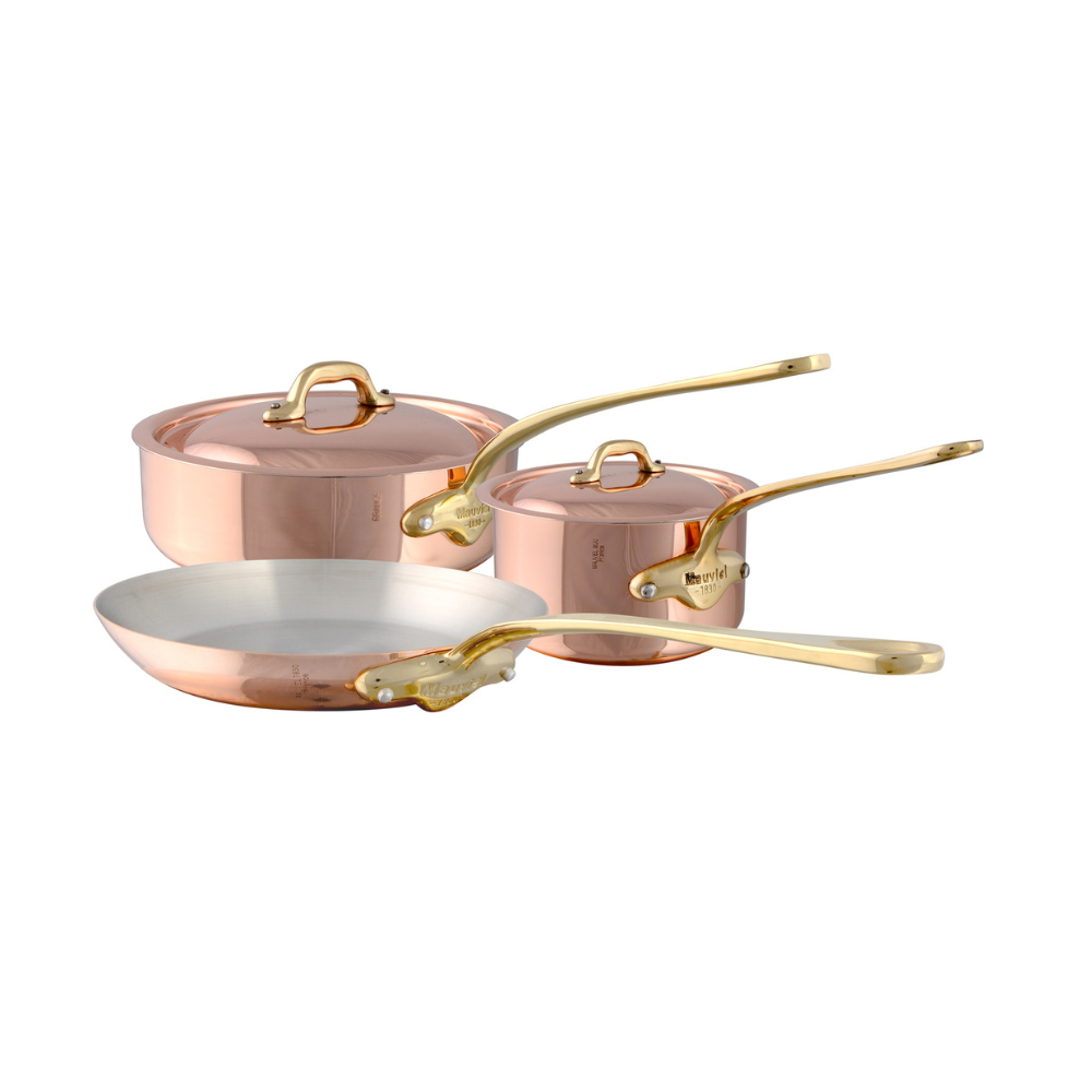 Mauviel M'Heritage M'150 B 5-piece copper cookware set with brass handles, including pots and pans on a kitchen countertop.